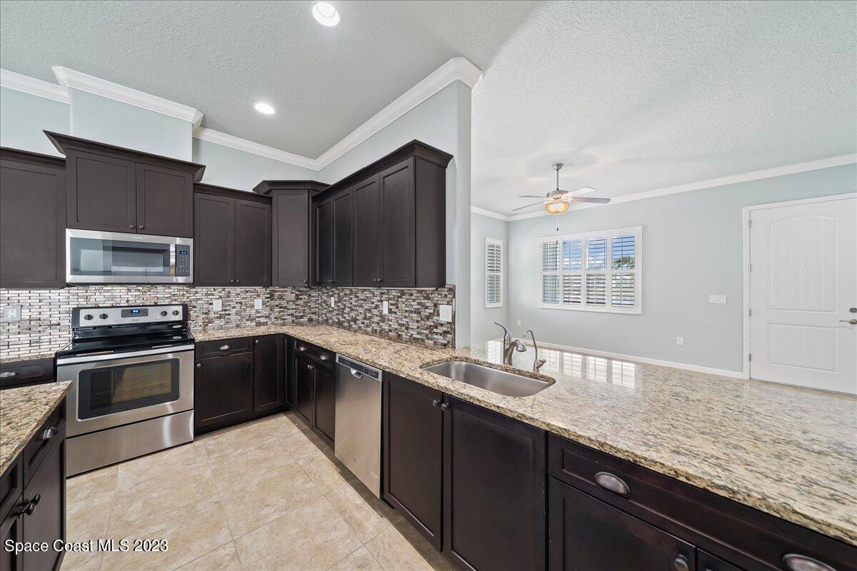603 Heming Way Melbourne, FL 32901 - Photo 14 of 45 a kitchen with stainless steel appliances granite countertop a sink stove microwave and refrigerator