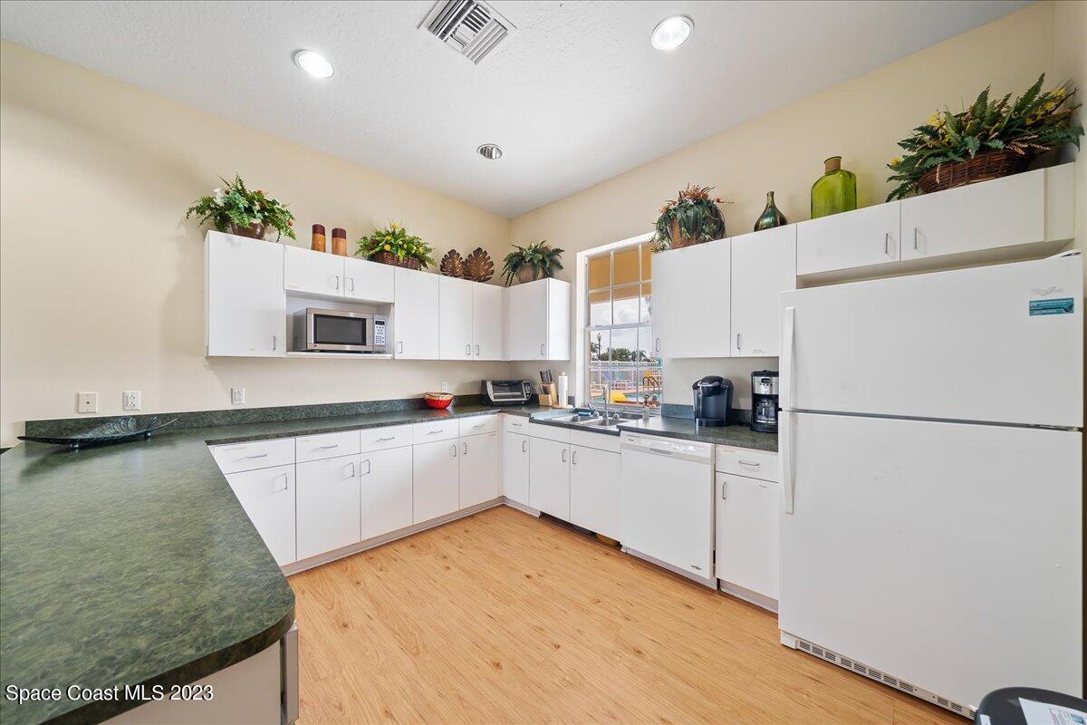603 Heming Way Melbourne, FL 32901 - Photo 39 of 45 a kitchen with sink a refrigerator and white cabinets