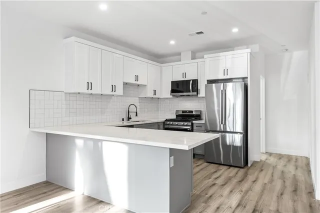 a kitchen with stainless steel appliances a refrigerator sink and white cabinets
