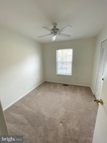 an empty room with a window and a ceiling fan
