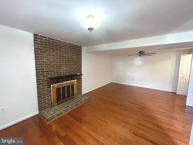 a view of empty room with wooden floor and fireplace