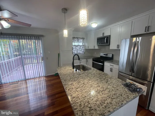 a kitchen with kitchen island granite countertop wooden cabinets a refrigerator and a stove