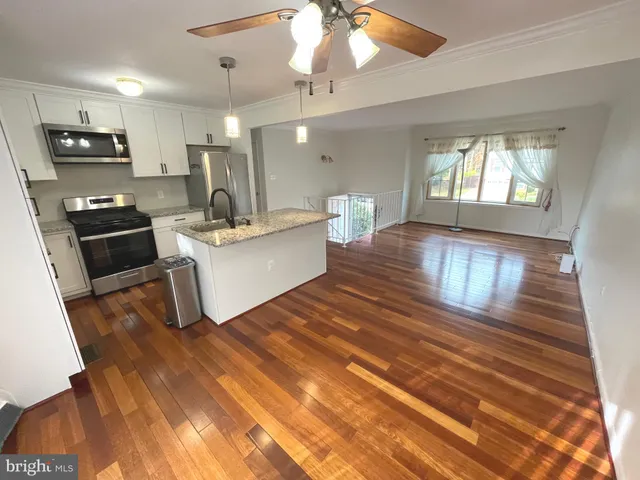 a living room with stainless steel appliances kitchen island granite countertop furniture a stove top oven a sink with kitchen island furniture and wooden floor