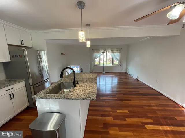 a kitchen with stainless steel appliances granite countertop a table chairs in it and wooden floors