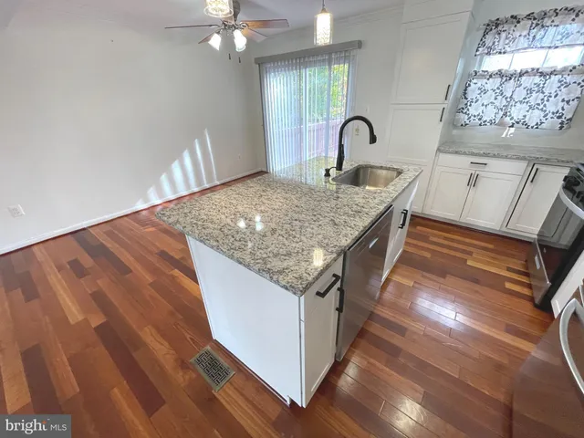a kitchen with granite countertop a stove a sink and a dining table with wooden floor