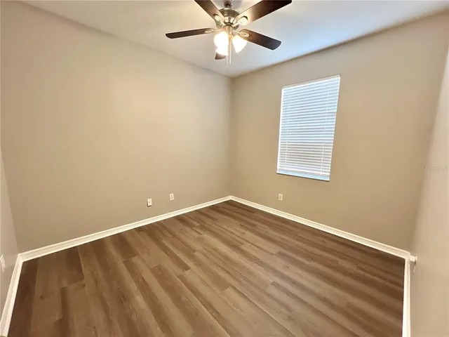 an empty room with a window and ceiling fan