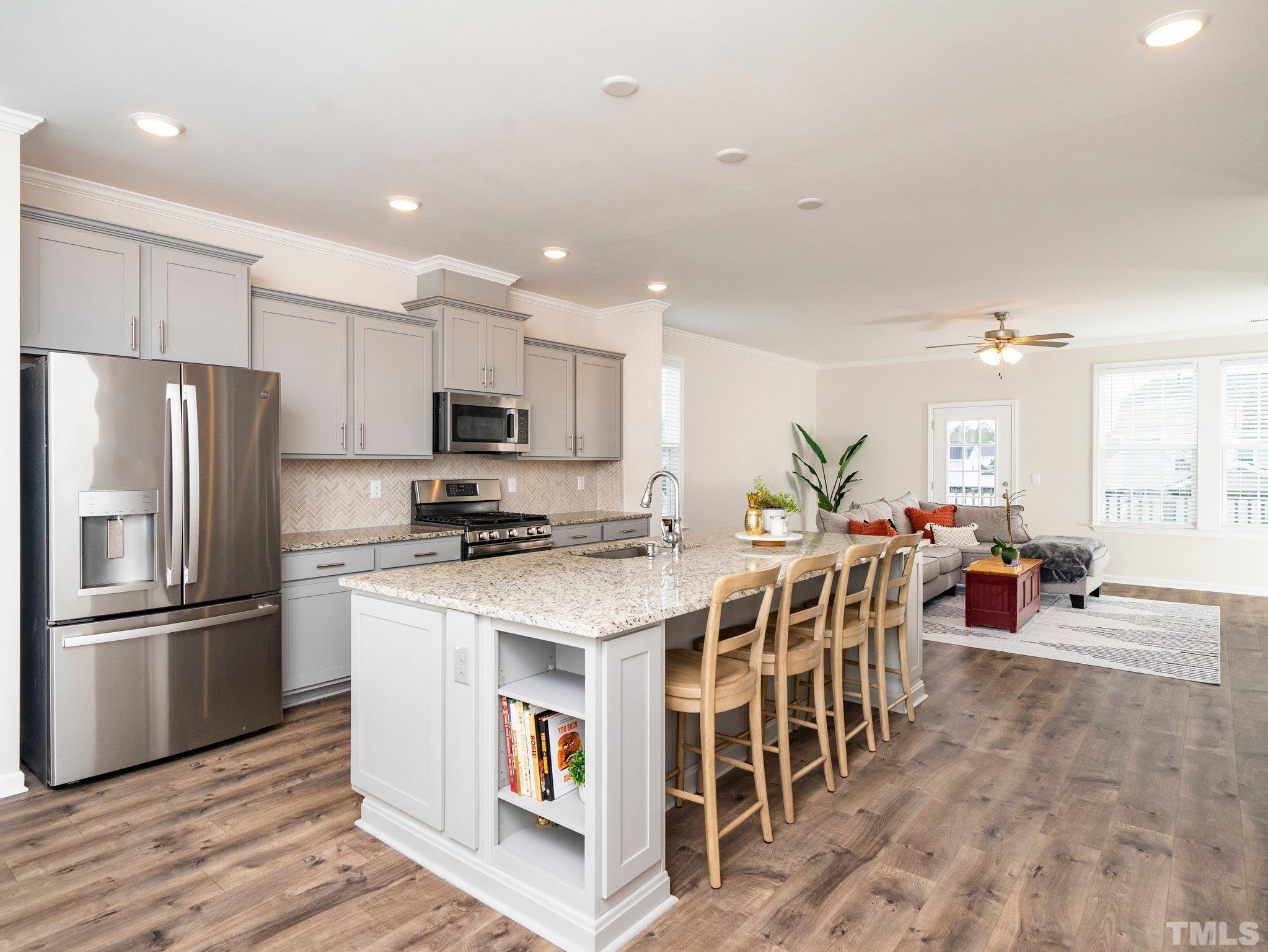 5915 Kayton Street Raleigh, NC 27616 - Photo 2 of 26 a kitchen with stainless steel appliances kitchen island granite countertop a table chairs microwave and view living room
