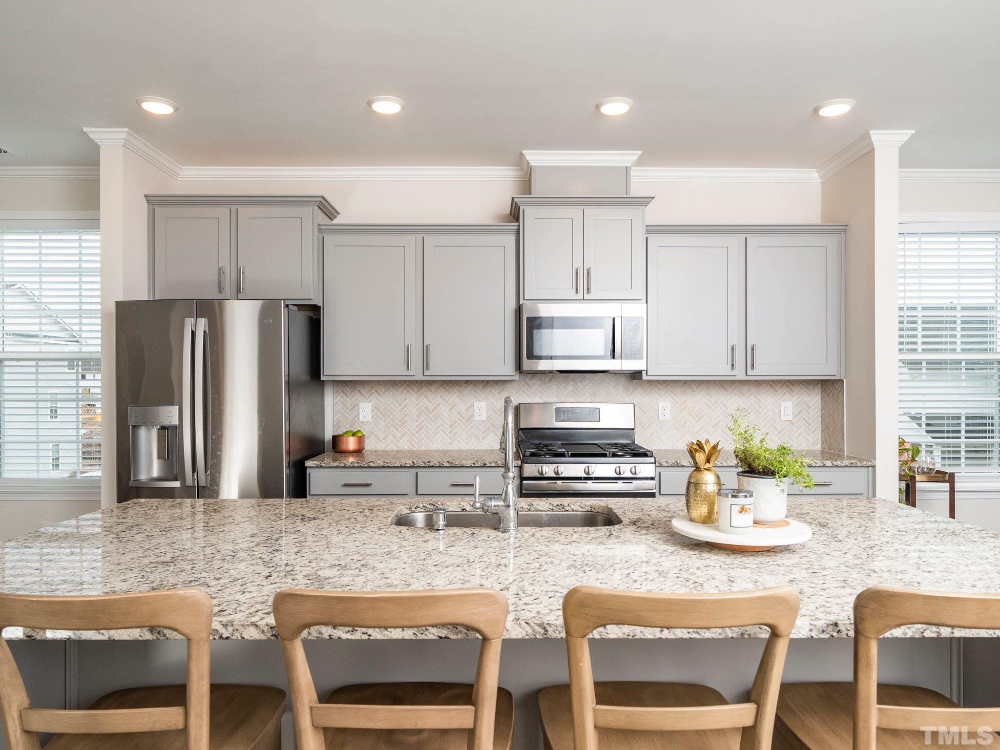 5915 Kayton Street Raleigh, NC 27616 - Photo 3 of 26 a kitchen with stainless steel appliances granite countertop a stove top oven a sink a refrigerator white cabinets and chairs
