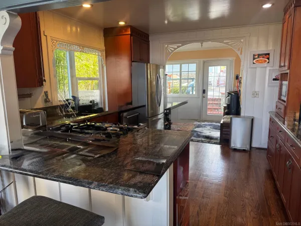 a kitchen with granite countertop wooden cabinets a sink and dishwasher a stove with wooden floor