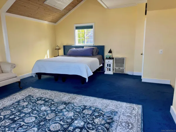 a spacious bedroom with a bed and wooden floor
