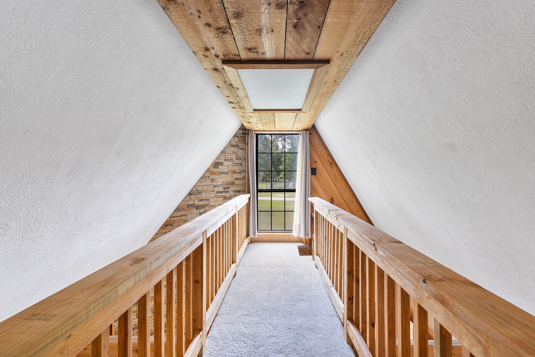 230 Walnut Drive Trinity, TX 75862 - Photo 17 of 48 A stylish catwalk overlooking the living room offers a dramatic vantage point to take in the home’s stunning architectural details, including the soaring stacked stone fireplace and rich natural wood accents.