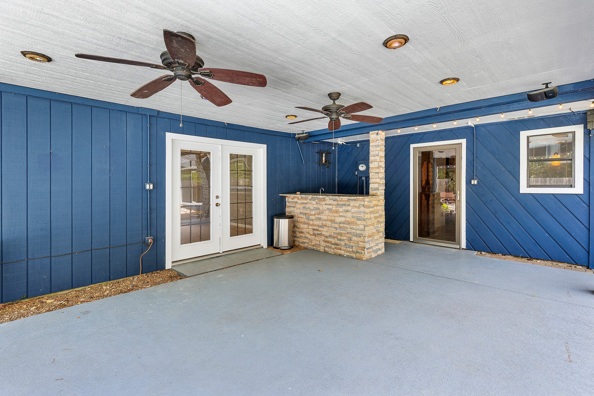 230 Walnut Drive Trinity, TX 75862 - Photo 26 of 48 The covered patio is an entertainer’s dream, thoughtfully equipped with ceiling fans, recessed lighting, and pre-wiring for sound to set the perfect mood. A sleek granite wet bar area with a built-in fridge makes outdoor hosting effortless—ideal for everything from summer cookouts to evening cocktails under the stars.