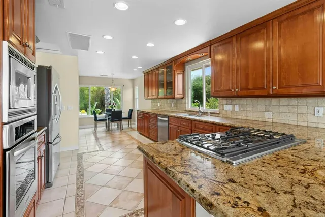 a kitchen with stainless steel appliances granite countertop a stove top oven a sink dishwasher and wooden cabinets with a granite countertops