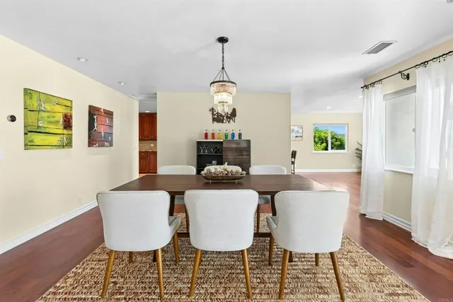 a dining room with wooden floor a chandelier a wooden table and chairs