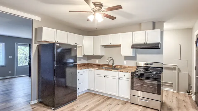 a kitchen with stainless steel appliances a refrigerator a stove a sink and white cabinets