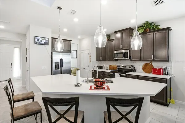 a kitchen with a dining table cabinets appliances and wooden floor