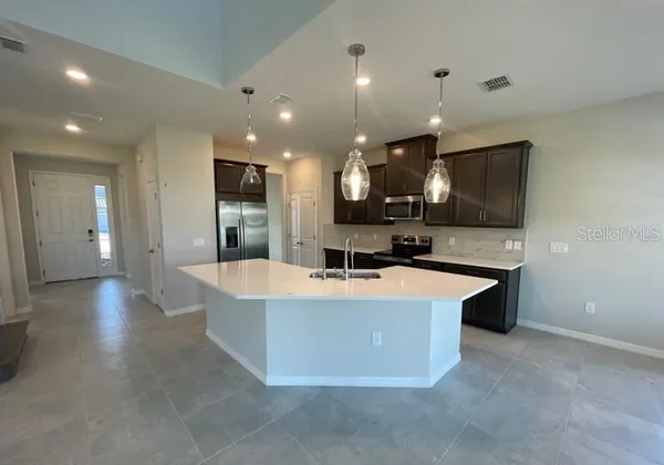 a view of kitchen with kitchen island a sink a stove and a refrigerator