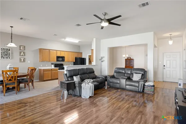 a living room with furniture kitchen view and a wooden floor