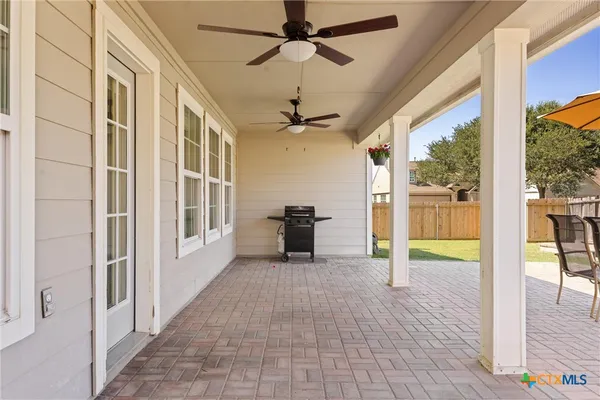 a patio with a table and chairs and potted plants