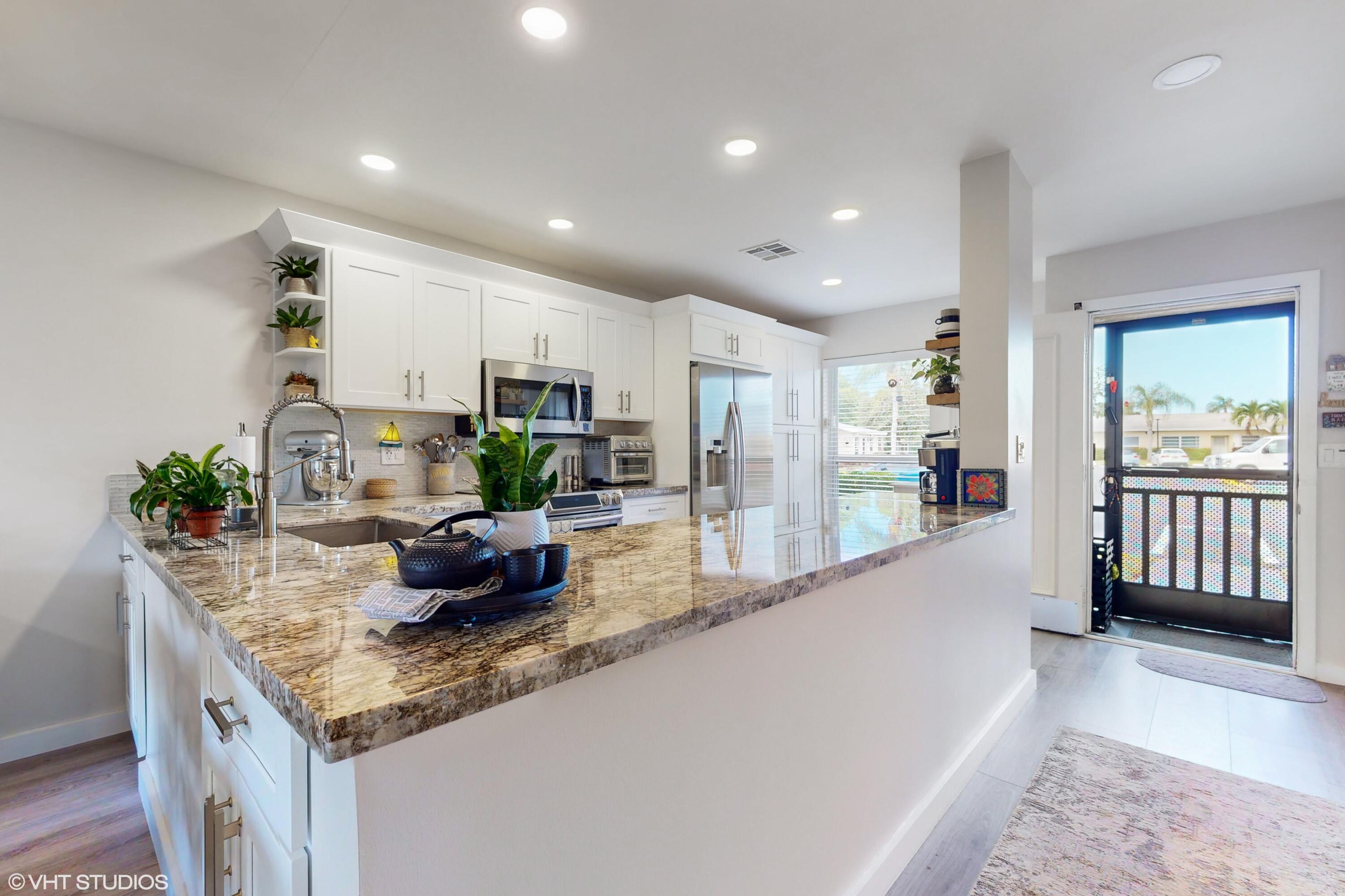 a kitchen with granite countertop kitchen island stainless steel appliances a sink and a counter top space
