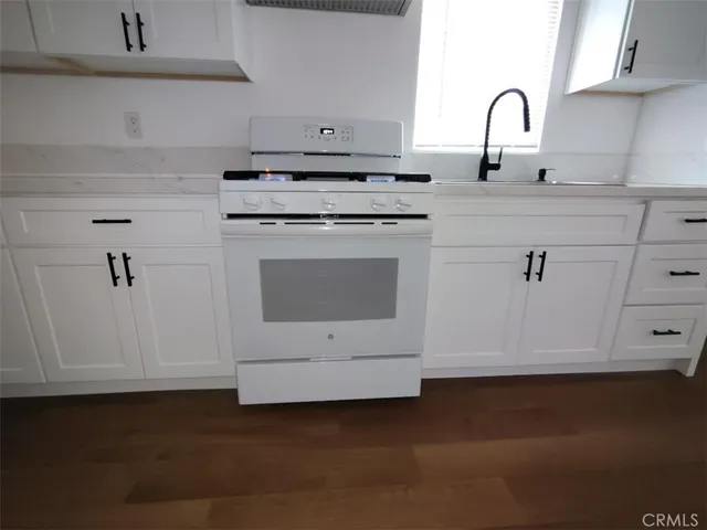 a kitchen with granite countertop white cabinets and white appliances