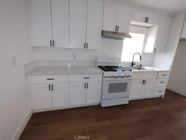 a kitchen with stainless steel appliances granite countertop a sink stove and white cabinets