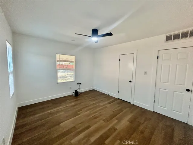 a view of an empty room with window and wooden floor