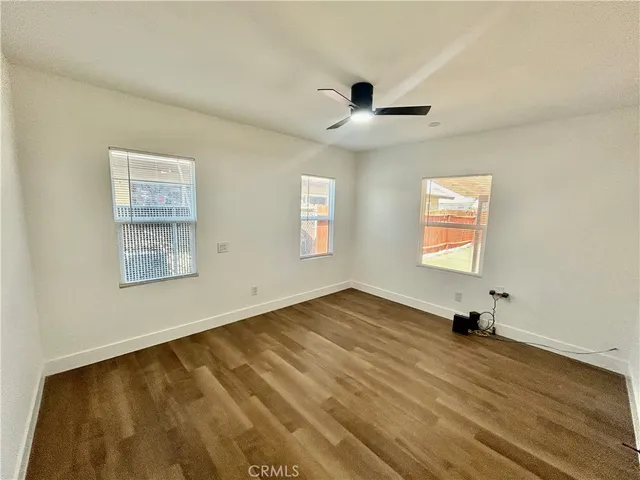 a view of empty room with wooden floor and fan