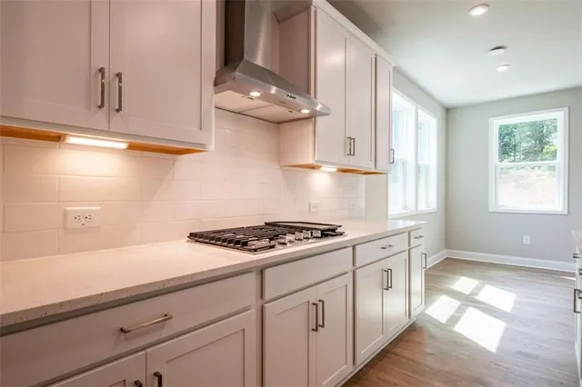 a kitchen with white cabinets and a stove with wooden floor