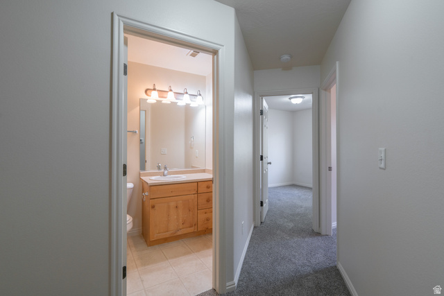 1735 West 540 North, Unit 1805 St. George, UT 84770 - Photo 54 of 64 Bathroom featuring a wood-finish vanity with a white countertop and basin sink, polished chrome faucet, and a four-light vanity fixture