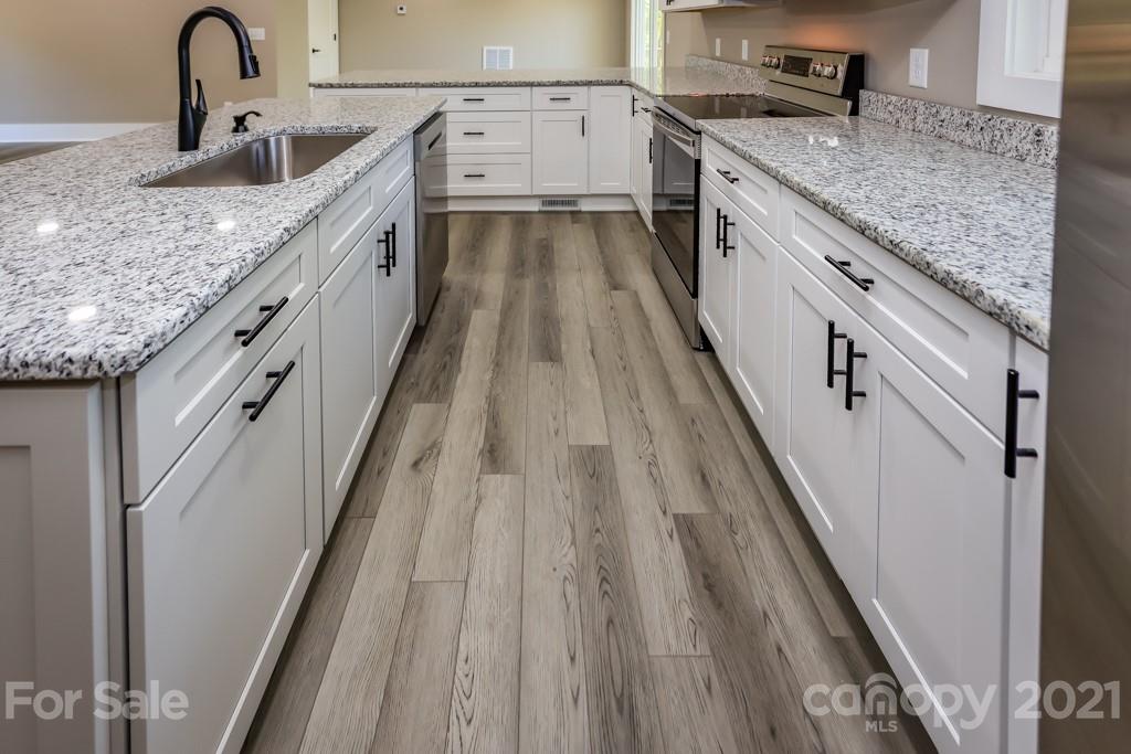 223 Hidden Hill Road Tryon, NC 28782 - Photo 8 of 27 a large kitchen with granite countertop a sink and dishwasher stove a refrigerator with wooden floor