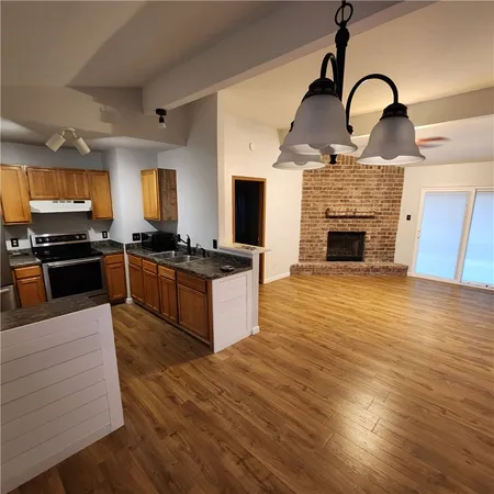 a large kitchen with stainless steel appliances granite countertop a stove top oven a sink dishwasher and wooden floor
