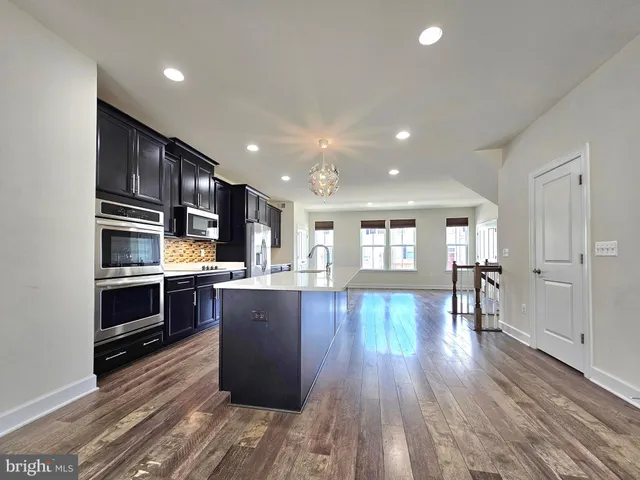 a kitchen with stainless steel appliances kitchen island granite countertop wooden floors and wooden cabinets