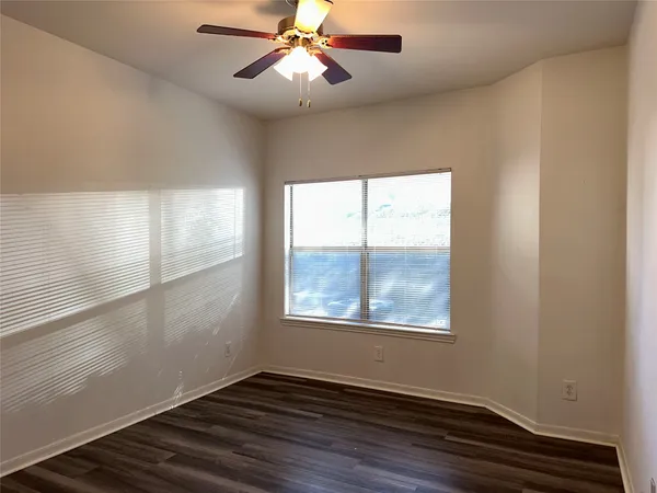 an empty room with wooden floor fan and windows