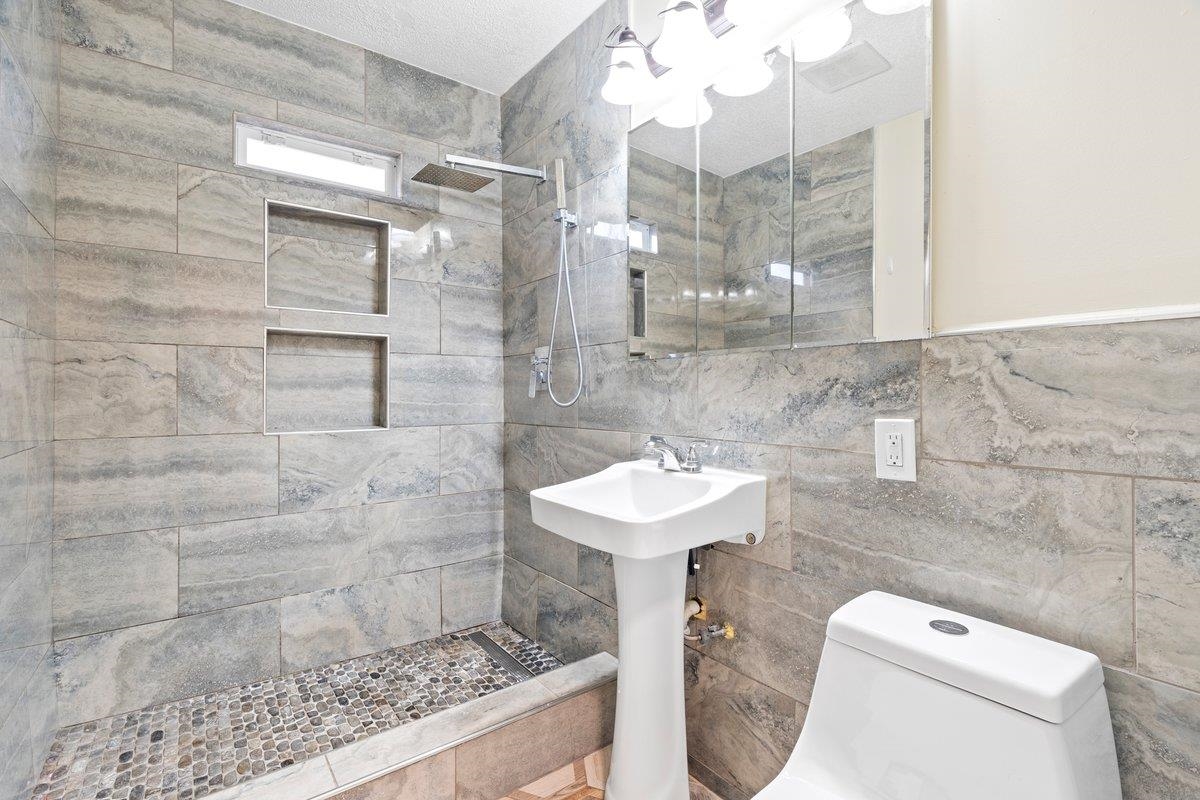 1012 Newell Road Memphis, TN 38111 - Photo 9 of 16 Bathroom featuring toilet, sink, tile walls, and a tile shower