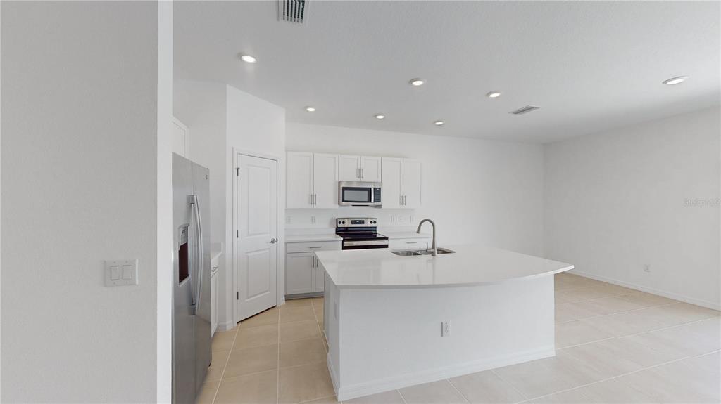2415 Paravane Way Wesley Chapel, FL 33543 - Photo 4 of 23 a kitchen with kitchen island a sink stainless steel appliances and white cabinets