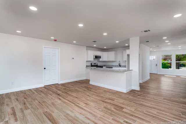 a view of kitchen with kitchen island white cabinets wooden floor and center island