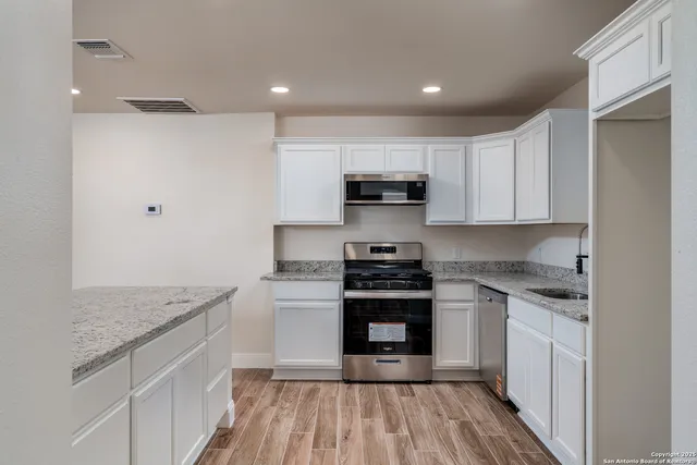 a kitchen with stainless steel appliances granite countertop a stove a sink and a refrigerator