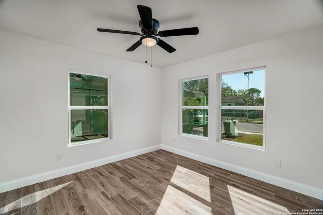 a view of an empty room with a window and wooden floor