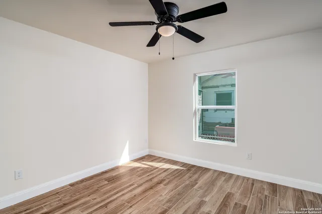 an empty room with a window and a ceiling fan