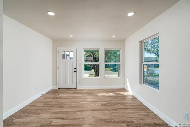an empty room with wooden floor and windows