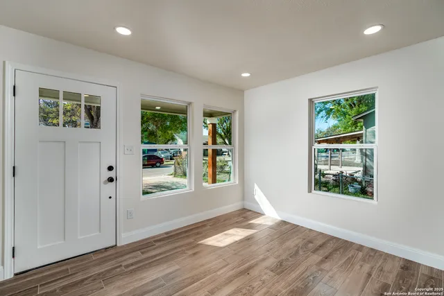 a view of an empty room with wooden floor and a window
