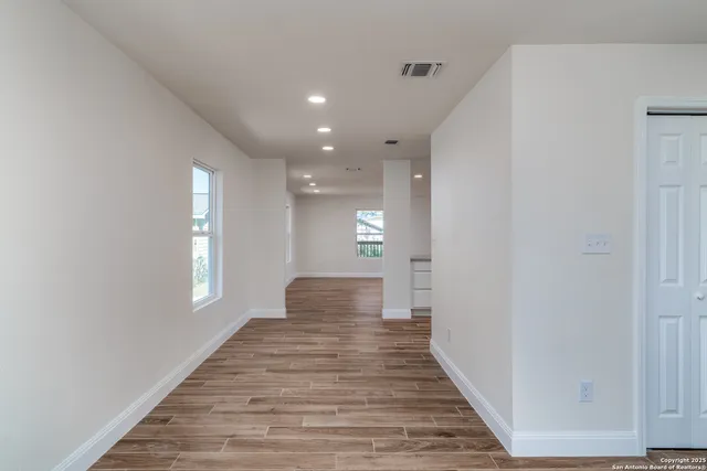 a view of a hallway with wooden floor and staircase