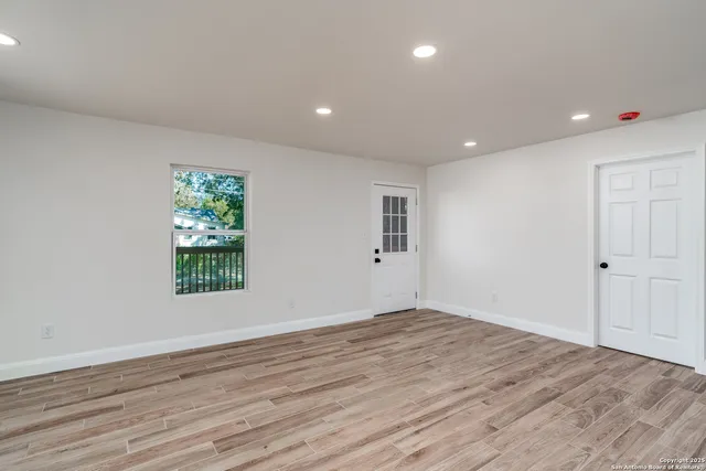 a view of an empty room with wooden floor and a window