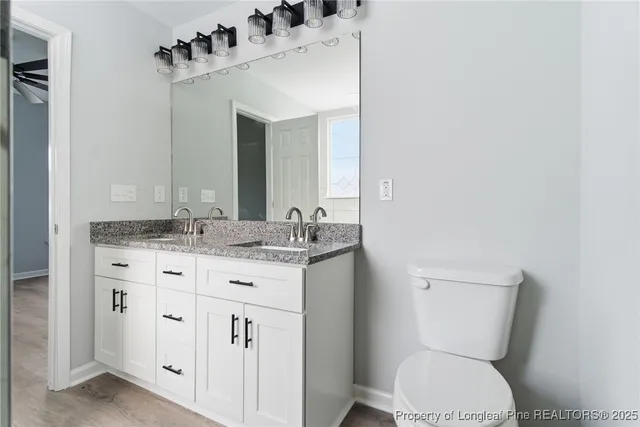 a bathroom with a granite countertop toilet sink and mirror