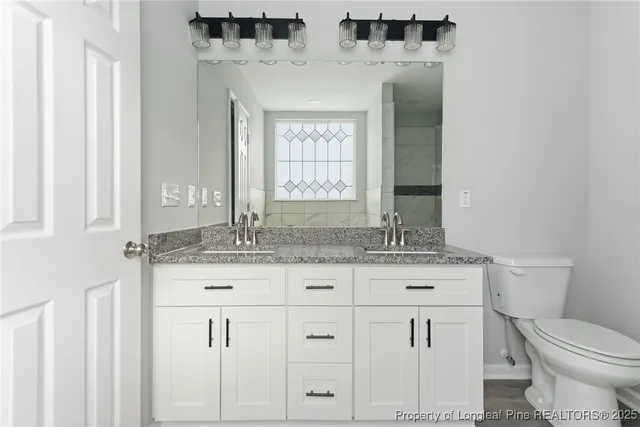a bathroom with a granite countertop toilet sink and mirror