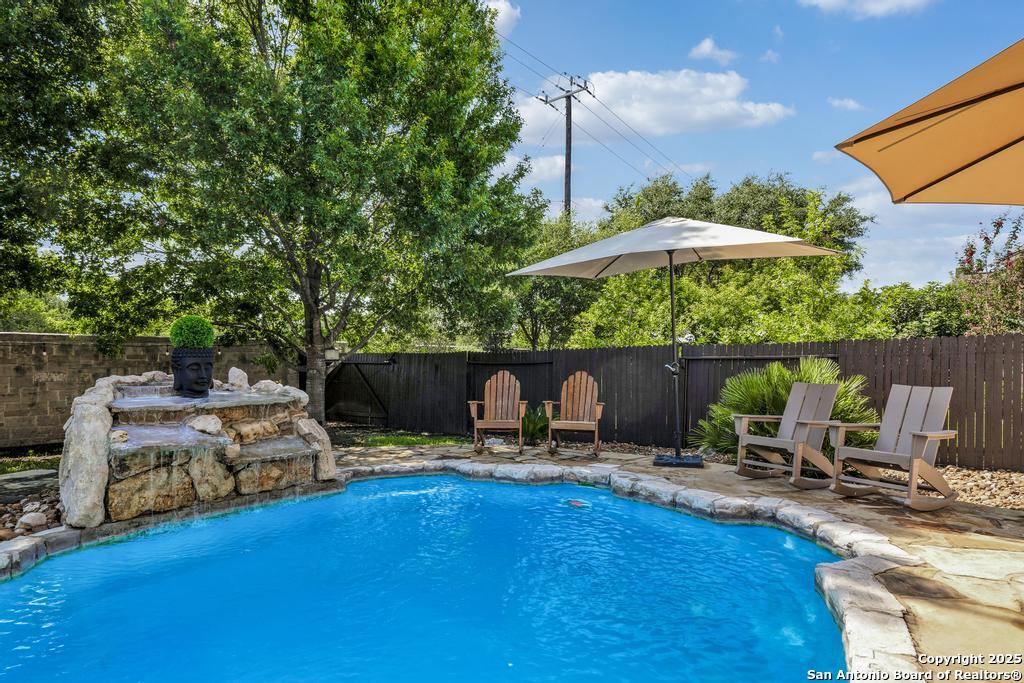 13326 Windmill Trace Helotes, TX 78023 - Photo 31 of 34 a view of a patio with table and chairs under an umbrella with wooden fence