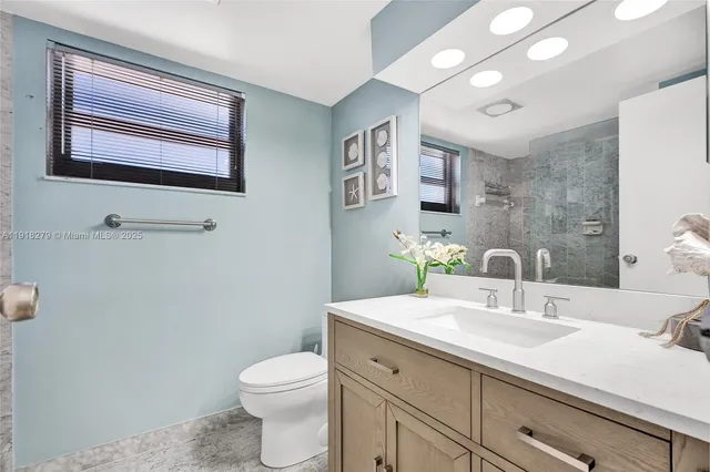 a bathroom with a granite countertop toilet sink and mirror