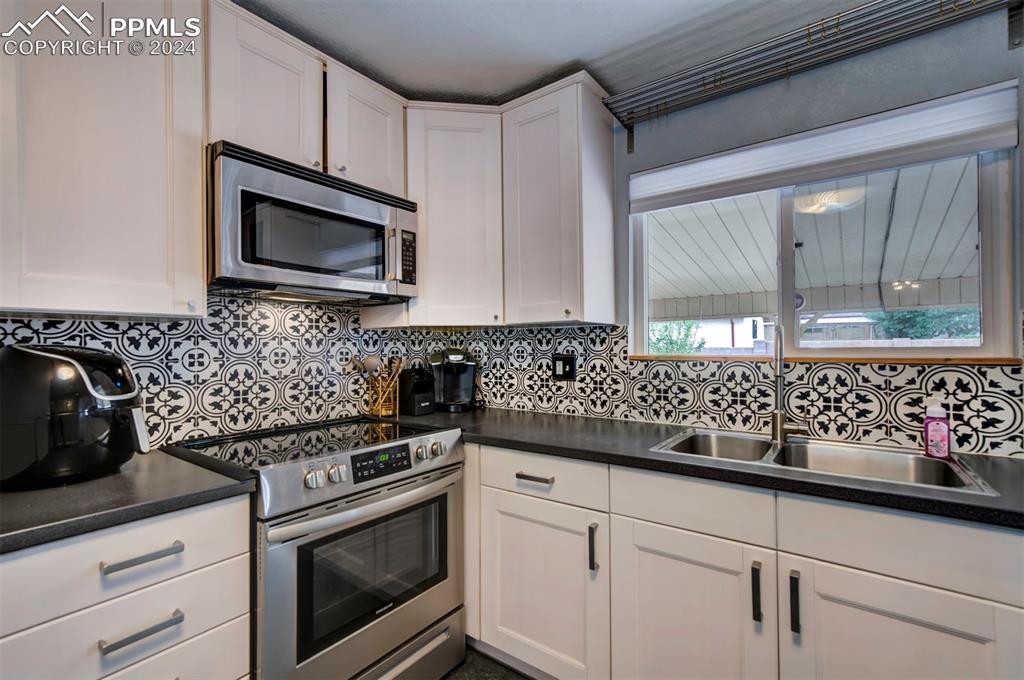 50 Duke Street Pueblo, CO 81005 - Photo 20 of 45 a kitchen with white cabinets a sink and a stove with wooden floor