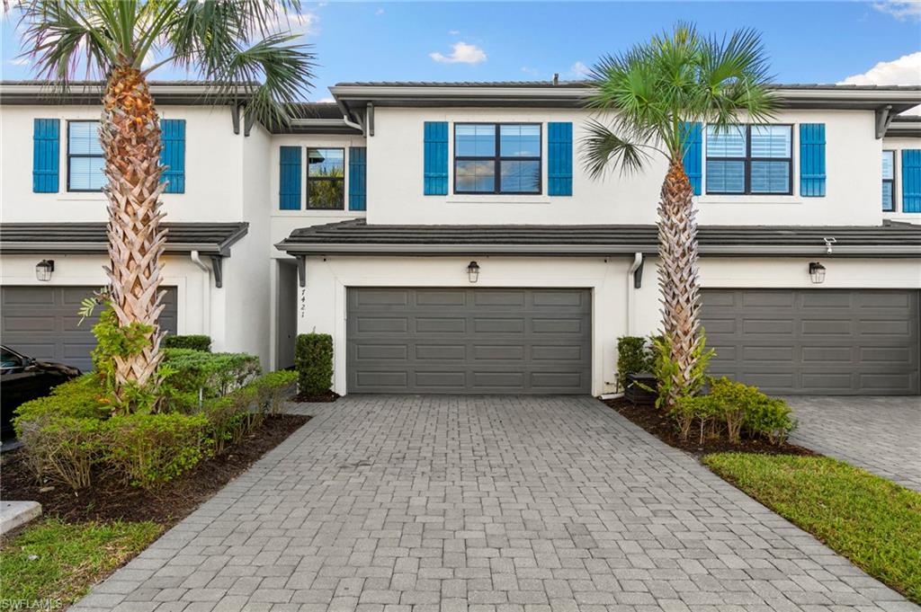 7421 Rockefeller Drive Naples, FL 34119 - Photo 2 of 37 a front view of a house with a garden and garage